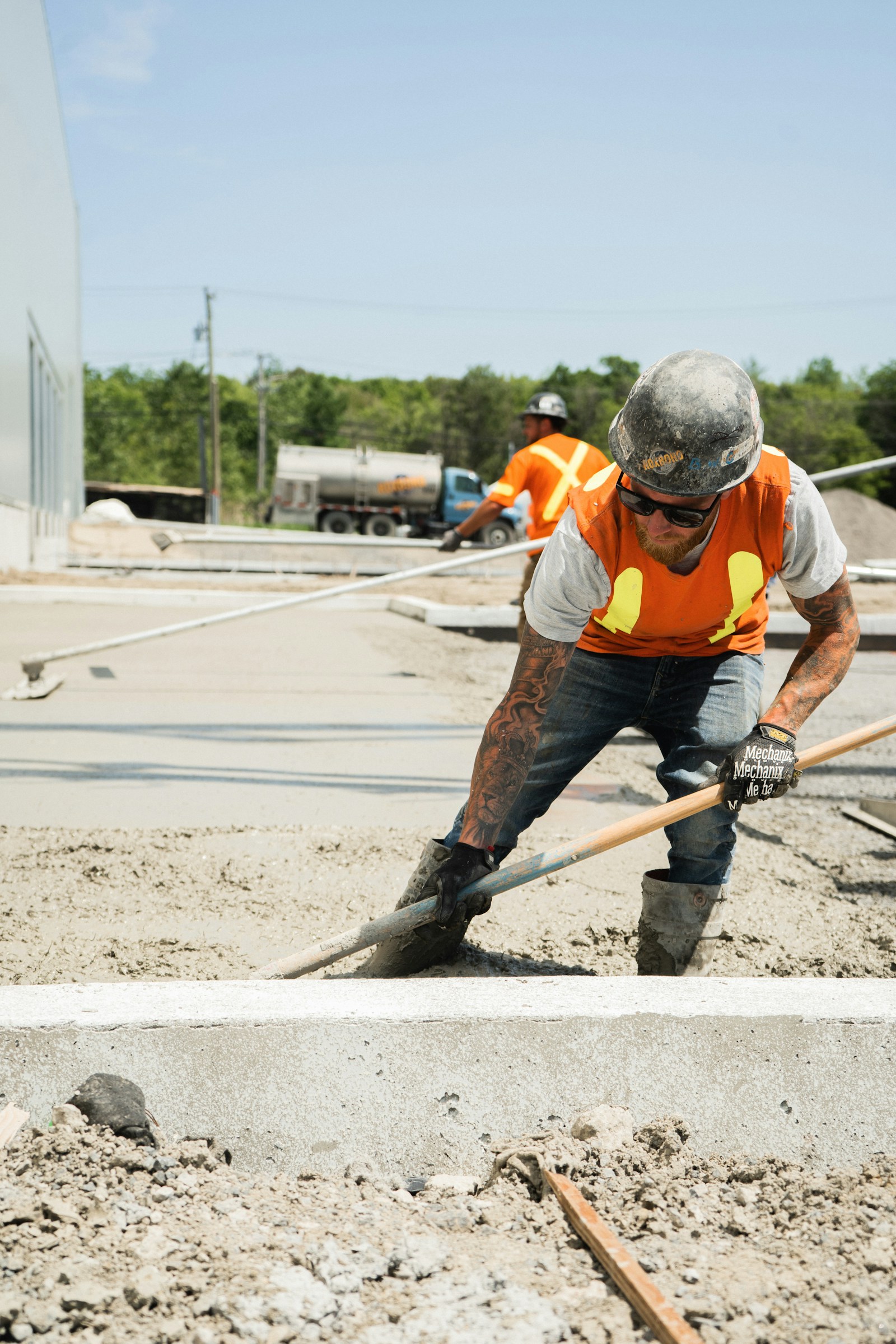 A concrete crew working on a fresh pour with a shovel and ready-mix truck.